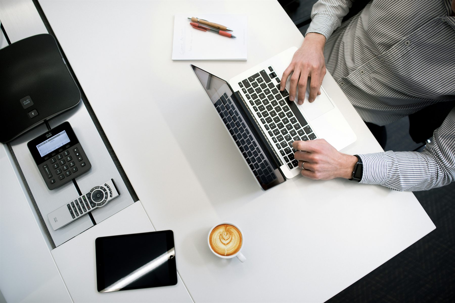 A desk with a calculator, notebook, laptop, and coffee for bookkeeping work